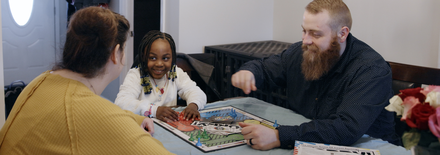 An adoptive family plays a board game together